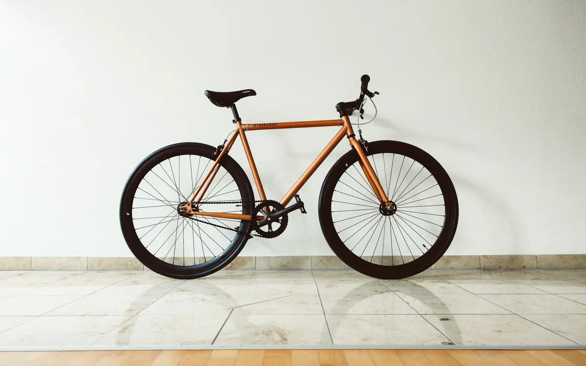 A bicycle leaning against a white wall in a bright hallway