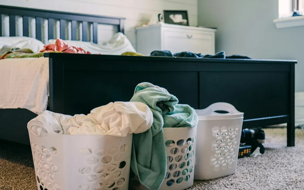 Dois cestos de roupa suja cheios ao pé da cama num quarto