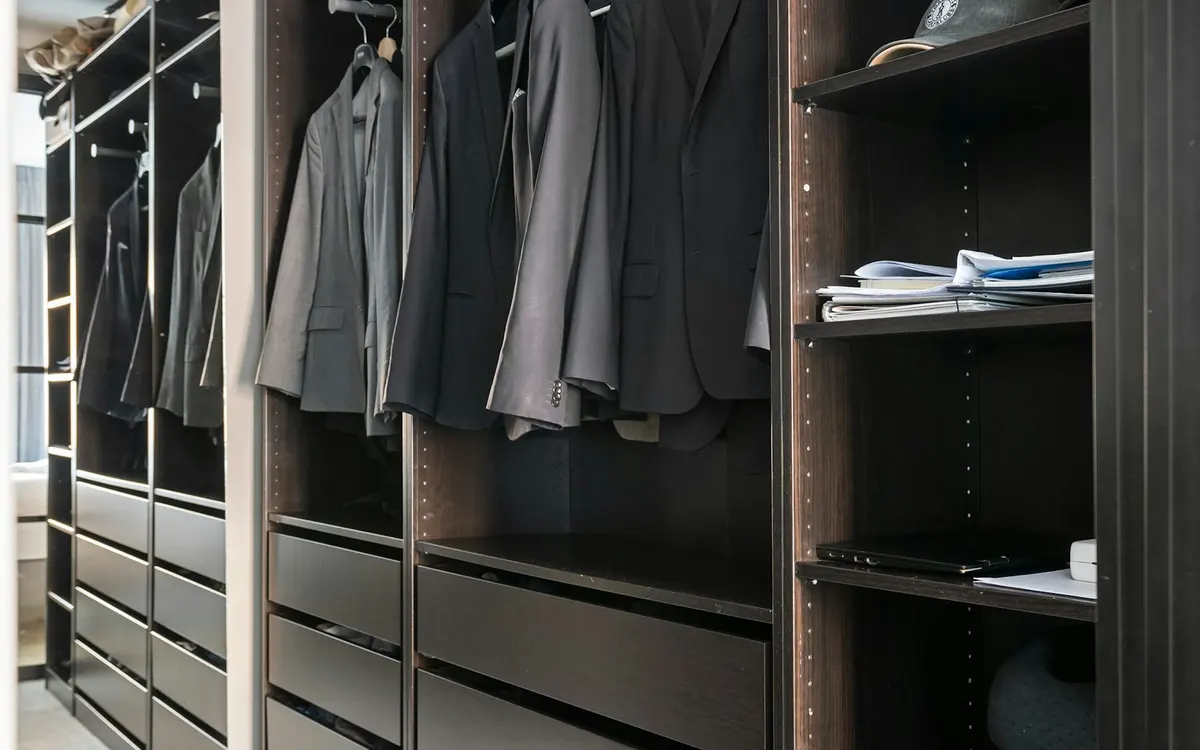 Dark wardrobe with folded and hanging clothes