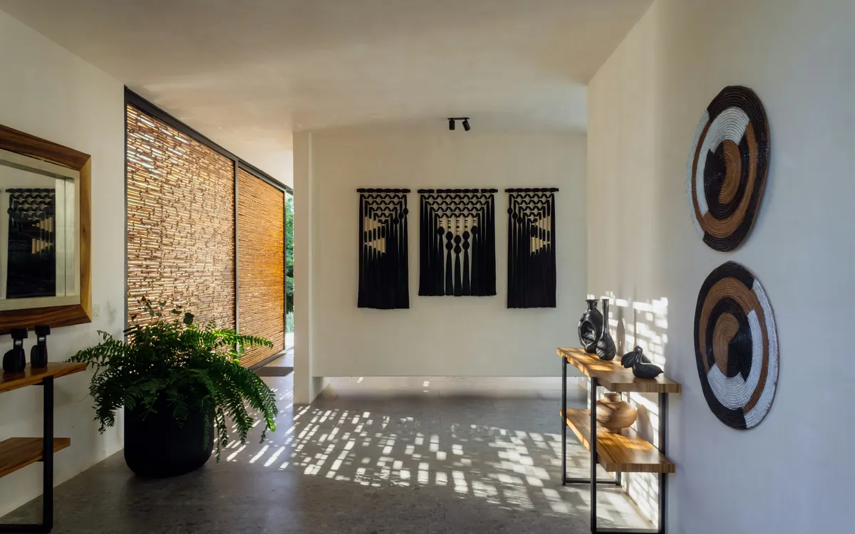 Hall de entrada com consolas estreitas, plantas e decoração de parede