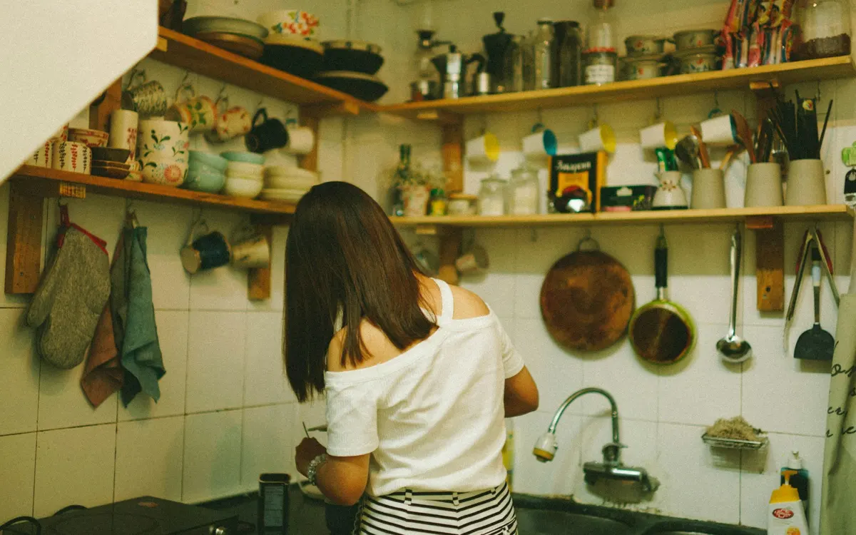 Pessoa a organizar utensílios em prateleiras de cozinha